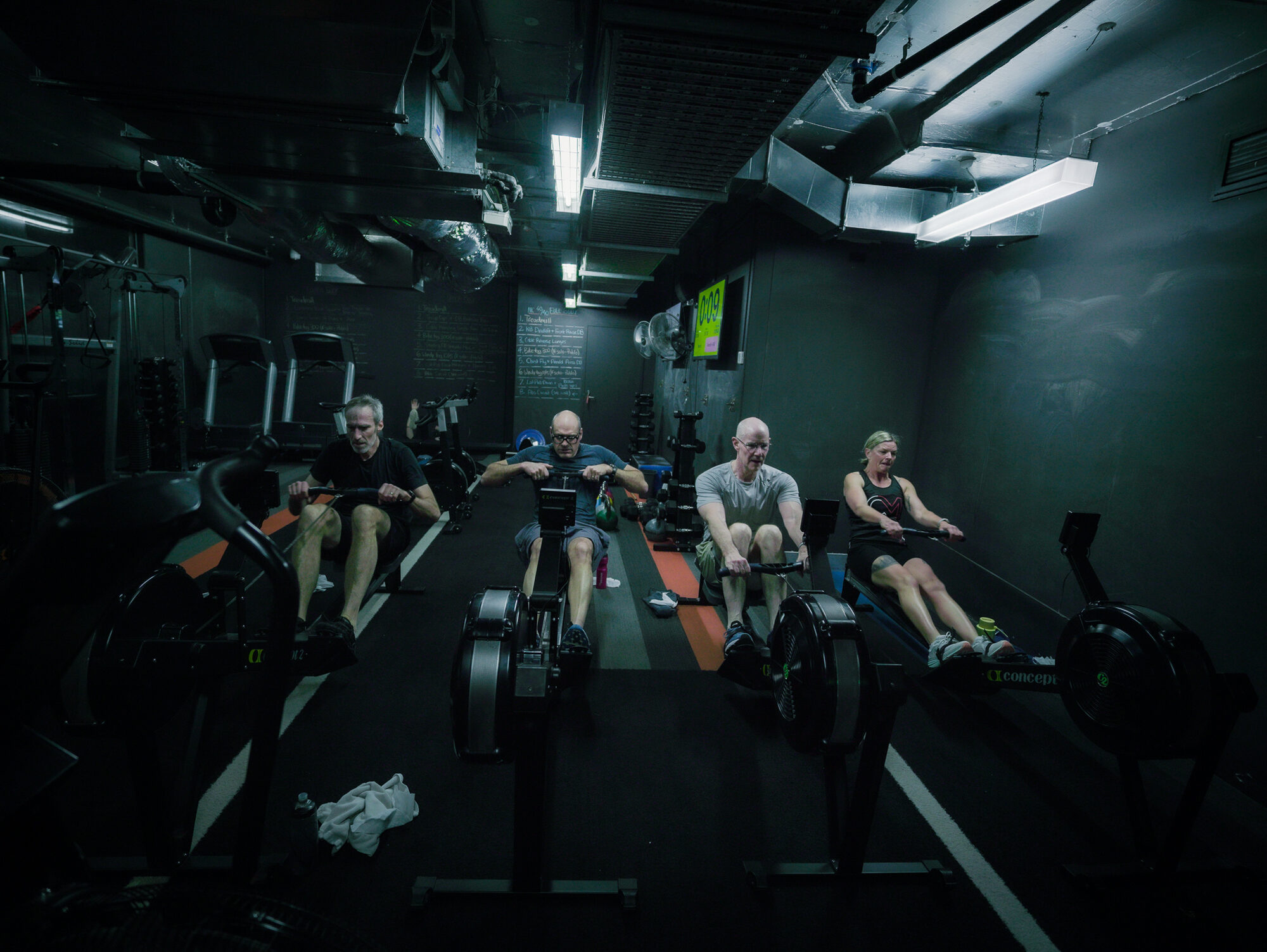A row of members on the rowers and air bikes early in the morning