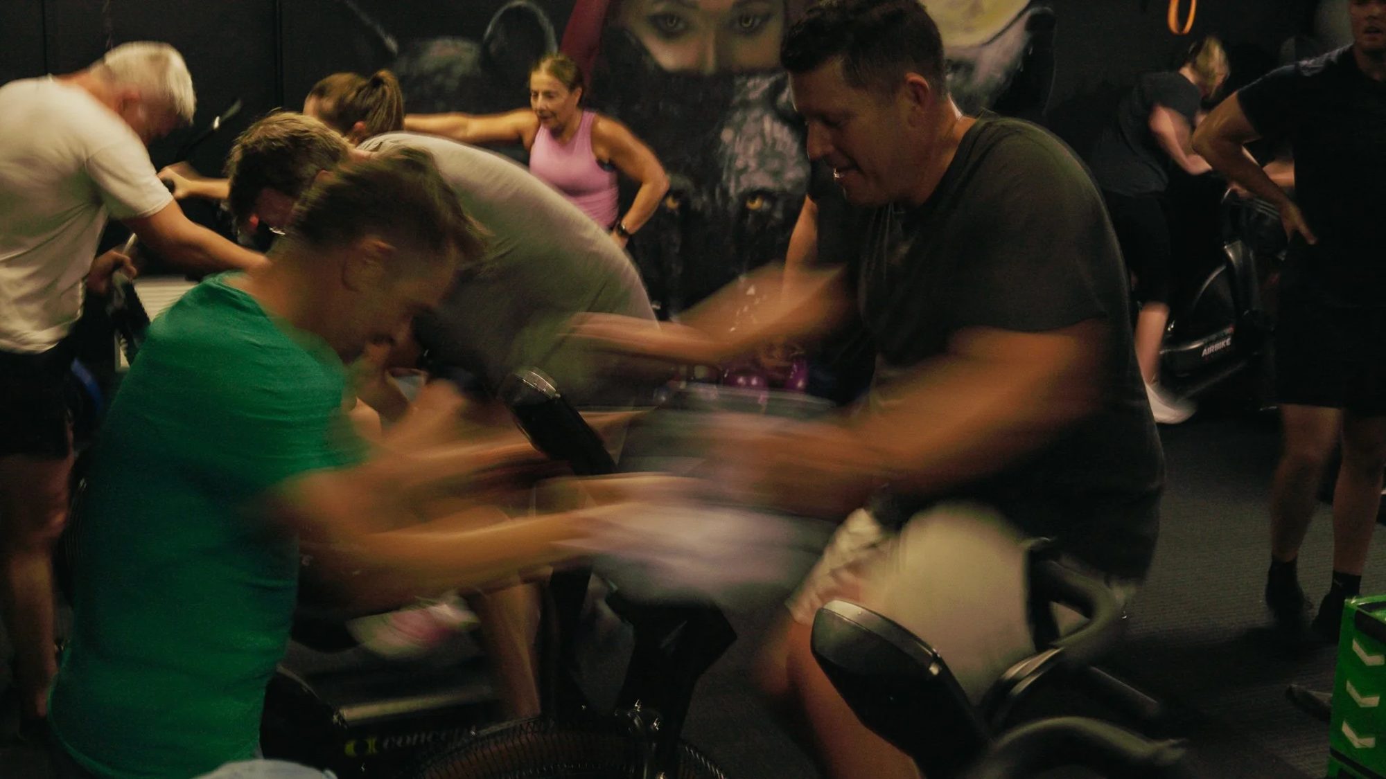 A full row of bikes and rowers mid-effort, members of every age working side by side