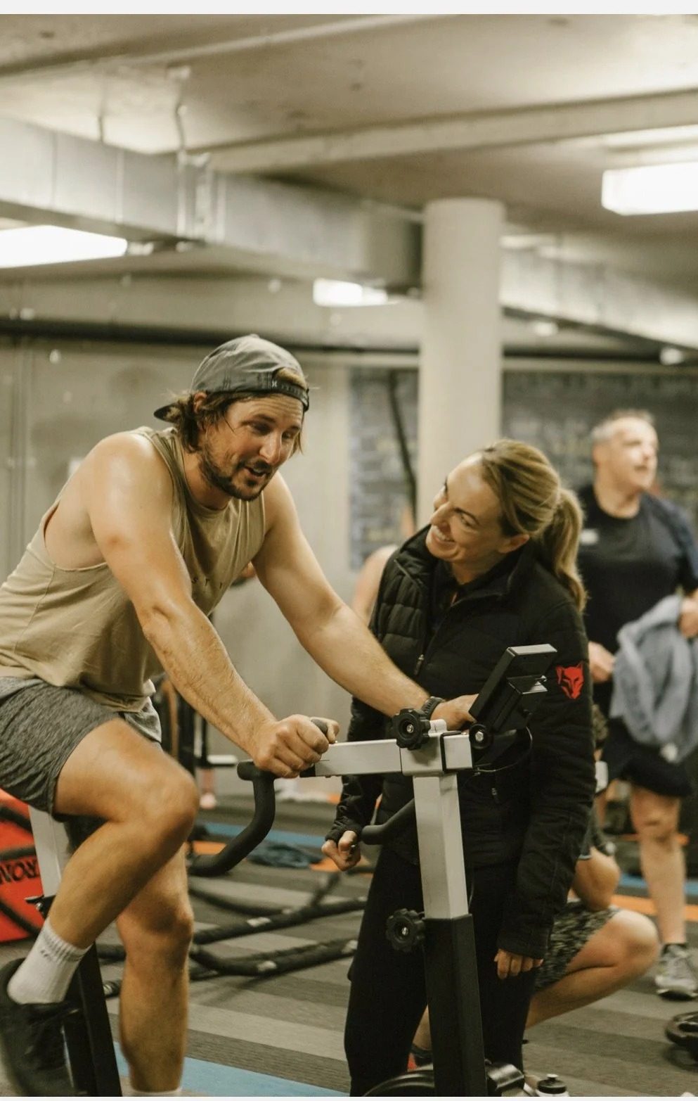 A coach working with a member on the bikes