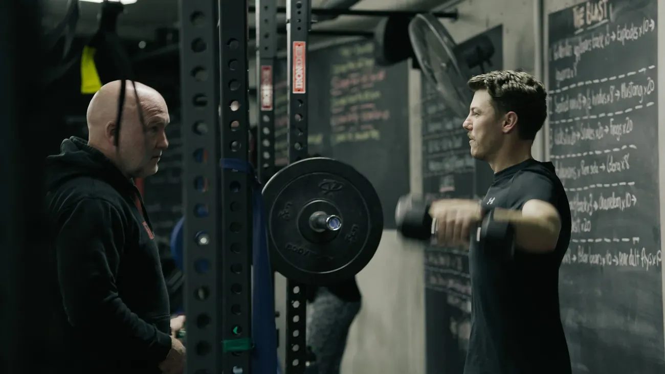 Mick Mackell coaching a member through a dumbbell raise