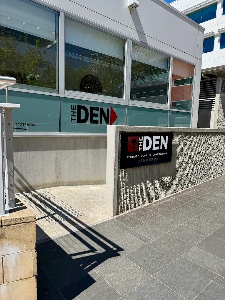 The Den Canberra sign on a low wall at the top of the ramp, with THE DEN and a red arrow on the window behind it